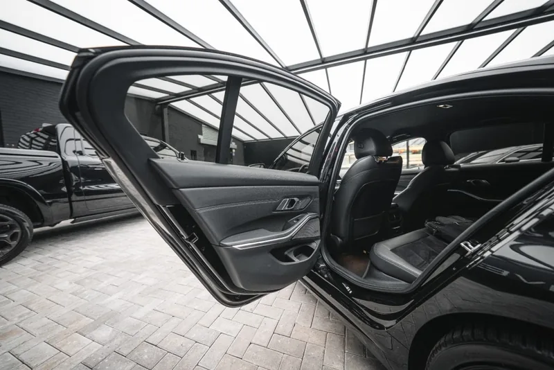 Achterbank van een BMW 3-Serie sedan met lederen bekleding en geopende achterdeur