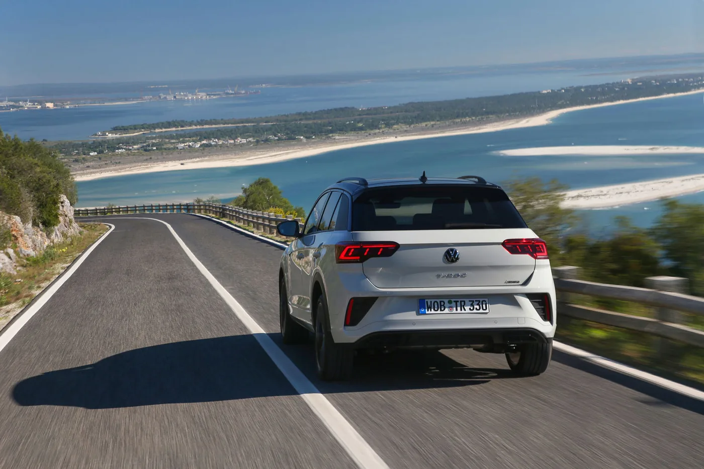 Rijdende Volkswagen T-Roc van achteren gezien op een kustweg